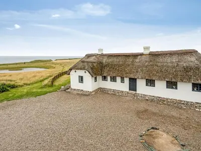 an old cottage with a thatched roof on the beach at Holiday Home Vili - 100m from the sea by Interhome in Lemvig