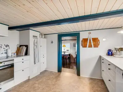 a kitchen with white cabinets and a wooden ceiling at Holiday Home Vili - 100m from the sea by Interhome in Lemvig