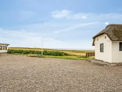 an old house with a thatched roof on a gravel road at Holiday Home Vili - 100m from the sea by Interhome in Lemvig