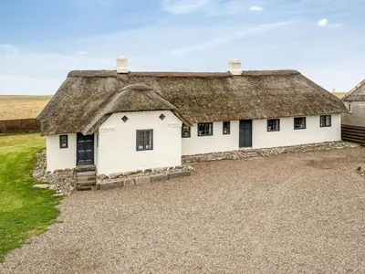 a cottage with a thatched roof on a gravel driveway at Holiday Home Vili - 100m from the sea by Interhome in Lemvig
