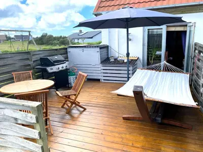 a patio with a hammock and a grill with an umbrella at Apartment Hansa - 300m from the sea by Interhome in Torsted