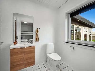 a bathroom with a toilet and a sink and a window at Holiday Home Darja - 300m from the sea by Interhome in Thyborøn