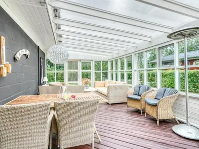 a conservatory with a table and chairs on a wooden deck at Holiday Home Lyra - 500m to the fjord by Interhome in Øsløs