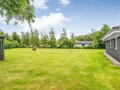 a large grassy yard with a house at Holiday Home Lyra - 500m to the fjord by Interhome in Øsløs