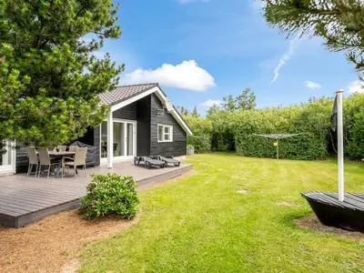 a black house with a deck and a yard at Holiday Home Lissi - 3-5km from the sea by Interhome in Brovst