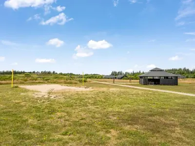 a field with a black building in the distance at Holiday Home Lissi - 3-5km from the sea by Interhome in Brovst