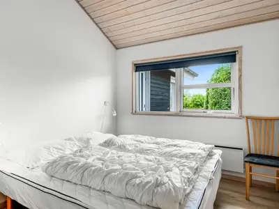 a white bedroom with a bed and a window at Holiday Home Lissi - 3-5km from the sea by Interhome in Brovst