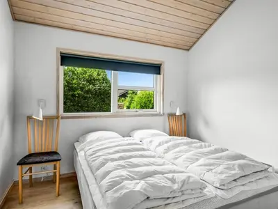 a bedroom with a large bed and a window at Holiday Home Lissi - 3-5km from the sea by Interhome in Brovst