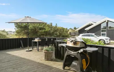 a motorcycle parked on a deck with an umbrella at Awesome Home In Løkken With Kitchen in Løkken