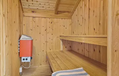 an inside of a wooden sauna with a red appliance at Awesome Home In Løkken With Kitchen in Løkken