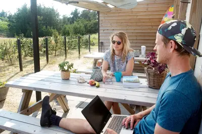 a man and a woman sitting at a picnic table with a laptop at Stone MT Garden Pod in Snedsted