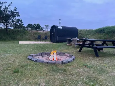 a fire pit in the grass next to a picnic table at Stone MT Garden Pod in Snedsted