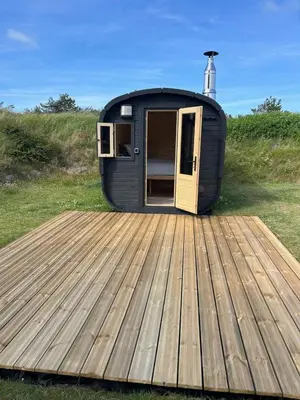 a black tiny house sitting on a wooden deck at Stone MT Garden Pod in Snedsted