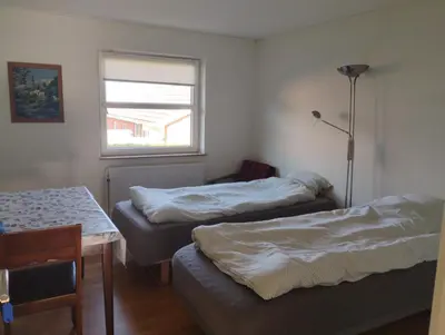 a room with two beds and a table and a window at Rødkælkevej's B&B in Hurup