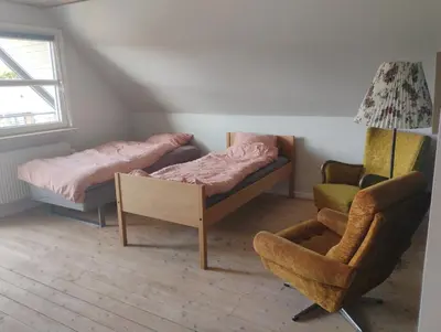 a room with two beds and a chair at Rødkælkevej's B&B in Hurup