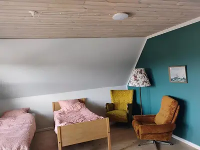 a bedroom with two beds and a chair at Rødkælkevej's B&B in Hurup