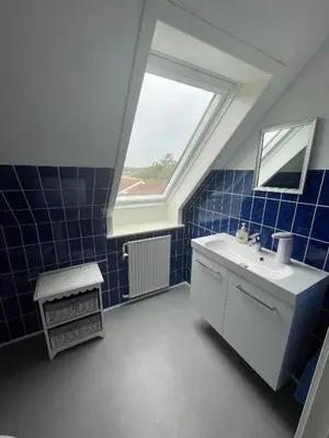 a blue tiled bathroom with a sink and a window at Rødkælkevej's B&B in Hurup