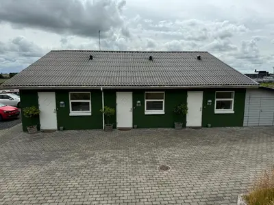 a green building with white doors and windows at Motel Gavlhuset in Nørager