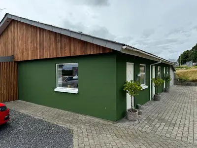 a green building with a car parked in front of it at Motel Gavlhuset in Nørager