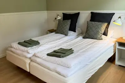 a large white bed with two green pillows on it at Motel Gavlhuset in Nørager