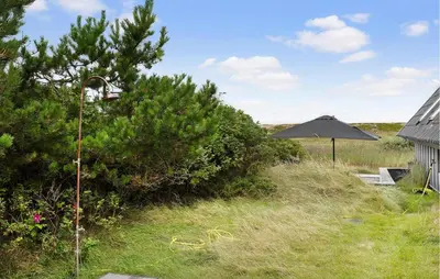 an umbrella in the grass next to a house at 3 Bedroom Stunning Home In Vestervig in Vestervig