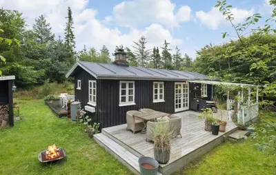 a black shed with a deck in a yard at Beautiful Home In Blokhus in Blokhus