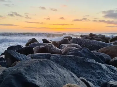 a group of rocks on the beach at sunset at 4 person holiday home in Thisted-By Traum in Thisted