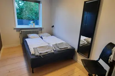 a small bedroom with a bed and a mirror at Centralt beliggende hyggeligt byhus med 8 sovepladser 130m2 med pejs in Holstebro