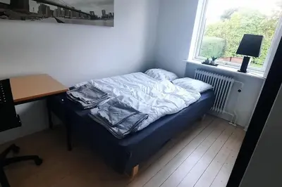 a small bed in a room with a desk and a window at Centralt beliggende hyggeligt byhus med 8 sovepladser 130m2 med pejs in Holstebro