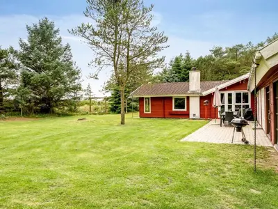 a red and white house with a yard at Holiday Home Aisling - 700m from the sea by Interhome in Brovst