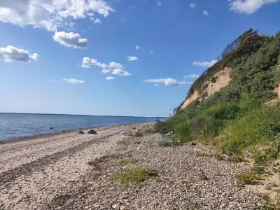 a rocky beach next to the ocean on a sunny day at Rustic Retreat in Gettrup - By Traum Ferienwohnungen in Sindrup