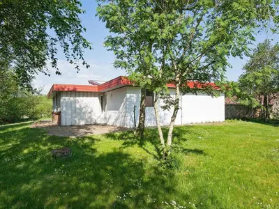 a small white house with a tree in the yard at 8 person holiday home in Hurup Thy-By Traum in Sindrup