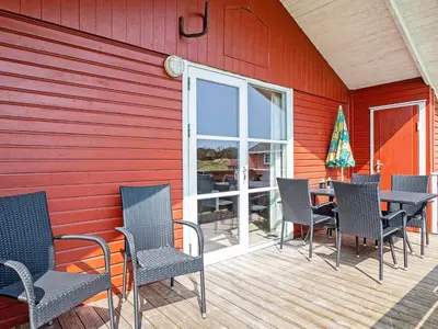 a patio with chairs and a table on a red wall at Family-friendly Retreat near Beach - By Traum Ferienwohnungen in Lild Strand