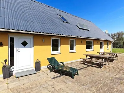 a yellow house with a bench and a picnic table at 10 person holiday home in Vinderup-By Traum in Vinderup