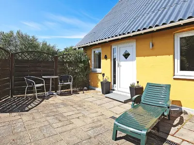 a patio with a table and chairs and a yellow house at 10 person holiday home in Vinderup-By Traum in Vinderup