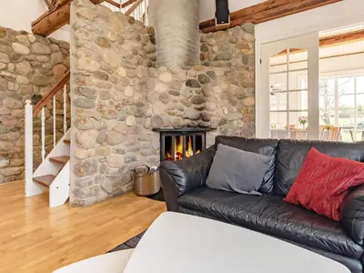 a living room with a leather couch and a stone wall at 8 person holiday home in Løgstrup-By Traum in Hjarbæk