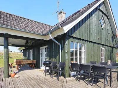 a green barn with chairs and a table on a deck at 8 person holiday home in Løgstrup-By Traum in Hjarbæk