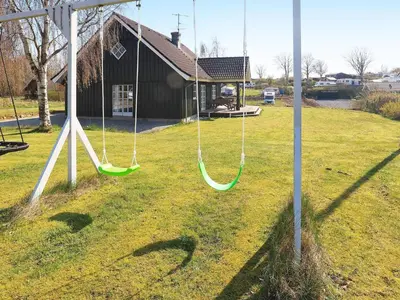 a swing set in a yard with a house at 8 person holiday home in Løgstrup-By Traum in Hjarbæk