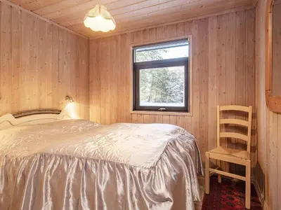 a bedroom with a bed and a window and a chair at 12 person holiday home in Pandrup-By Traum in Rødhus