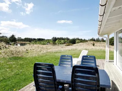 a blue table and chairs on a porch with a field at Luxury Pool Villa Retreat - By Traum Ferienwohnungen in Blokhus