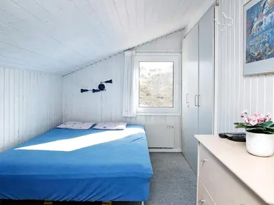 a small bedroom with a blue bed and a window at Luxury Pool Villa Retreat - By Traum Ferienwohnungen in Blokhus