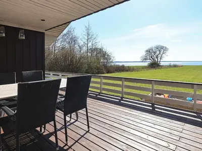 a wooden deck with a table and chairs on it at Fjordview Retreat with Spa - By Traum Ferienwohnungen in Sillerslev