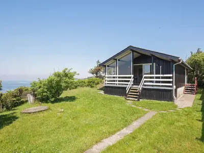 a small house on a hill with a grass yard at 7 person holiday home in Struer-By Traum in Remmer Strand