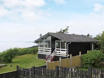 a small black cottage with a wooden fence at 7 person holiday home in Struer-By Traum in Remmer Strand