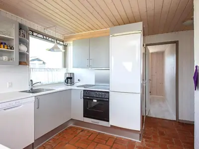 a kitchen with white cabinets and a stove and a refrigerator at Panoramic Sea View Retreat - By Traum Ferienwohnungen in Blokhus