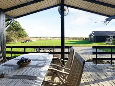 a table and chairs on a deck with a view of a field at 4 person holiday home in Hurup Thy-By Traum in Sindrup