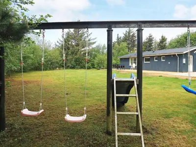 a swing set in a yard with a ladder at 5 person holiday home in Thyholm-By Traum in Sindrup