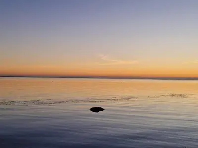 a rock in the water on the beach at sunset at 5 person holiday home in Thyholm-By Traum in Sindrup