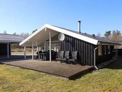 a house with a wooden deck with chairs on it at 6 person holiday home in Blokhus in Blokhus