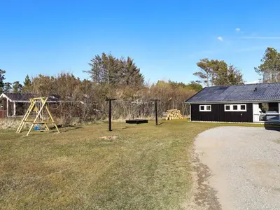 a yard with a swing set and a playground at 6 person holiday home in Blokhus in Blokhus